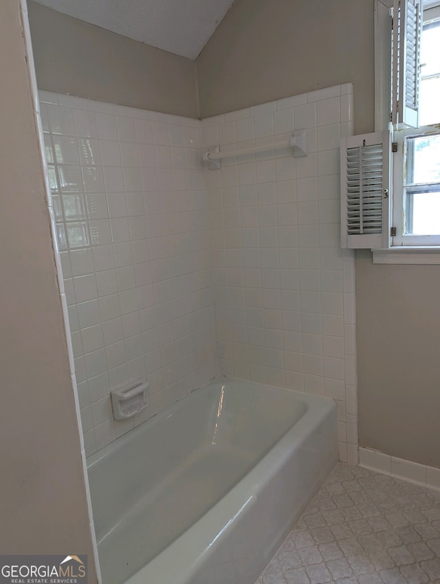 bathroom featuring tiled shower / bath combo, tile patterned flooring, and vaulted ceiling