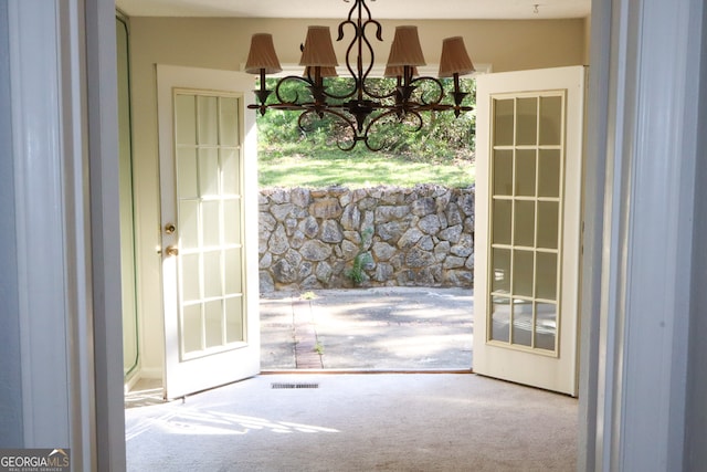 doorway featuring a notable chandelier and carpet floors