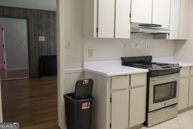 kitchen with a textured ceiling, light hardwood / wood-style floors, stainless steel stove, white cabinetry, and backsplash