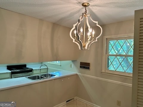 kitchen featuring black gas stove, a chandelier, a textured ceiling, and sink