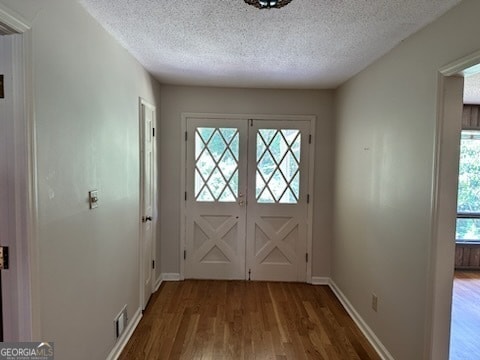 doorway to outside with french doors, hardwood / wood-style floors, a textured ceiling, and a healthy amount of sunlight