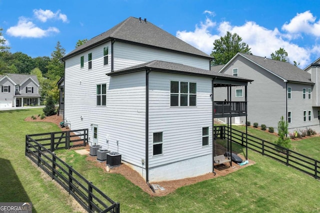 rear view of house featuring cooling unit and a lawn