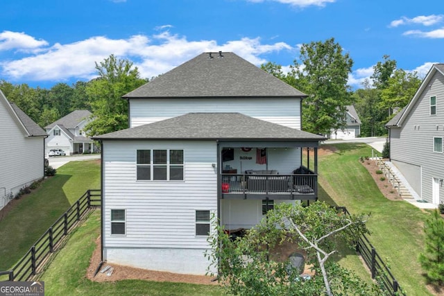 rear view of property featuring a balcony and a yard