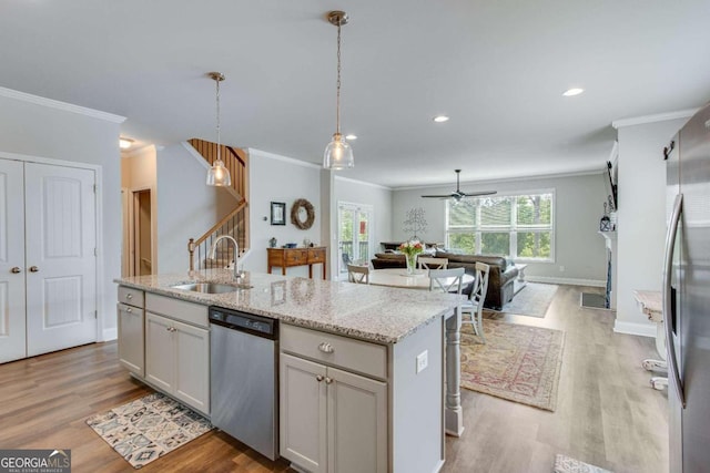 kitchen with appliances with stainless steel finishes, light hardwood / wood-style flooring, sink, an island with sink, and ceiling fan