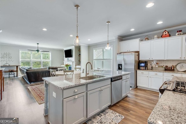 kitchen with sink, light hardwood / wood-style floors, ceiling fan, stainless steel appliances, and a center island with sink