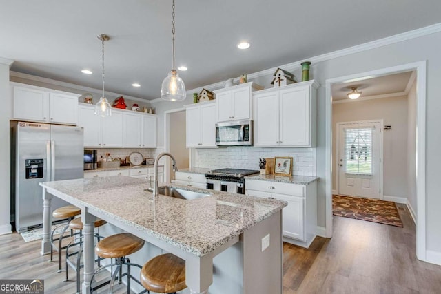 kitchen featuring decorative backsplash, appliances with stainless steel finishes, hardwood / wood-style flooring, sink, and crown molding