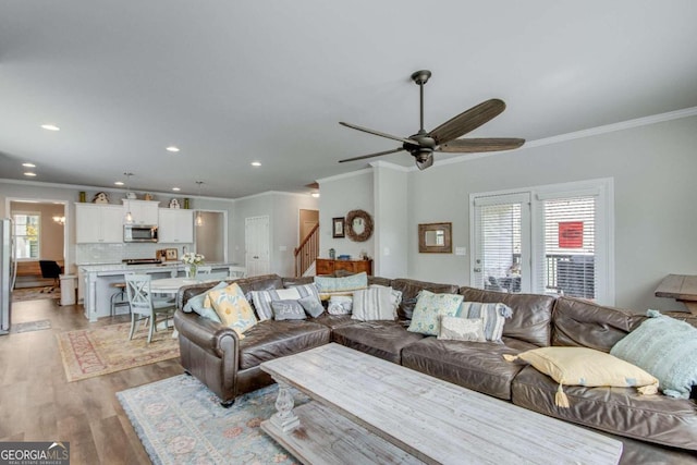 living room with ceiling fan, light hardwood / wood-style flooring, and ornamental molding