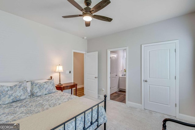 bedroom featuring ceiling fan, light colored carpet, and ensuite bathroom