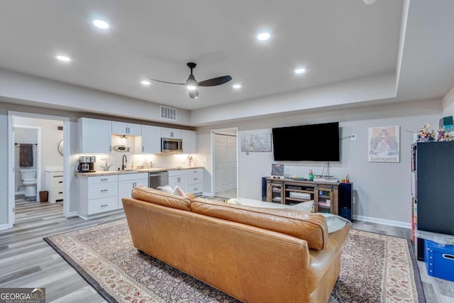 living room with ceiling fan, sink, and light hardwood / wood-style flooring