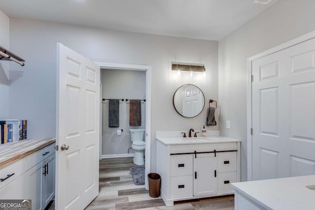 bathroom with hardwood / wood-style floors, toilet, and vanity