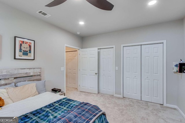 carpeted bedroom with ceiling fan and multiple closets