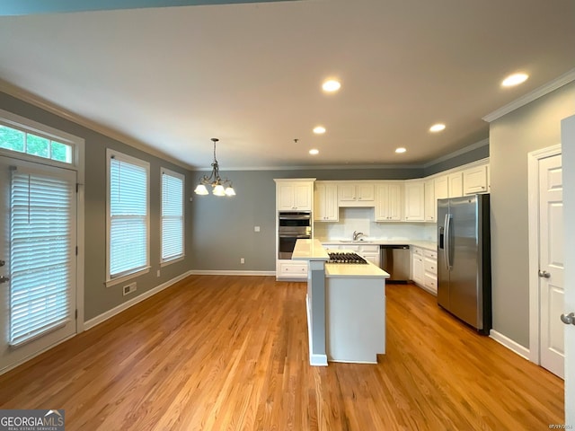 kitchen with white cabinets, appliances with stainless steel finishes, light hardwood / wood-style floors, and a chandelier