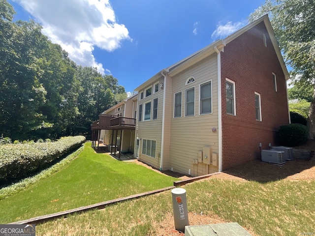 back of property featuring central air condition unit and a lawn