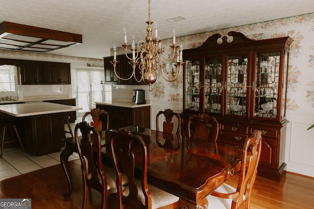 dining room featuring light wood-type flooring, sink, a textured ceiling, and a chandelier