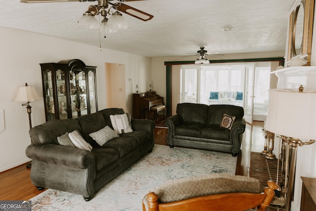 living room featuring hardwood / wood-style flooring, a textured ceiling, and ceiling fan