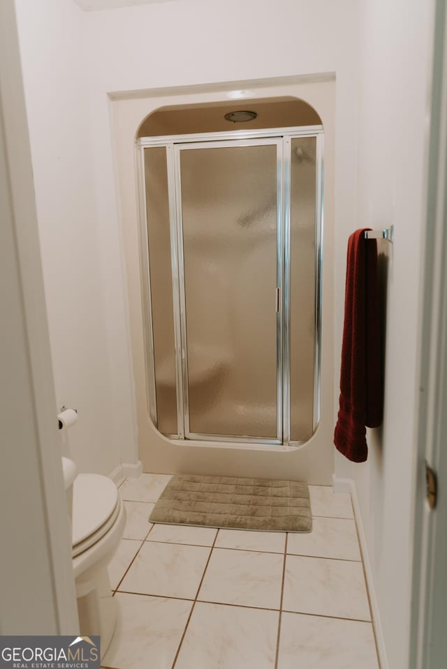 bathroom featuring walk in shower, tile patterned floors, and toilet