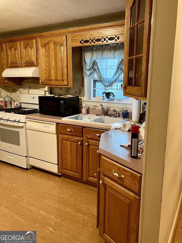 kitchen featuring a textured ceiling, sink, light hardwood / wood-style flooring, and white appliances