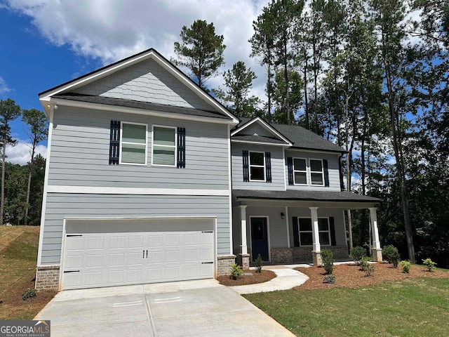 view of front of property with covered porch, a garage, and a front yard