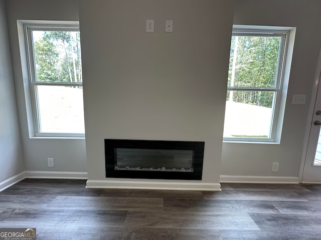 unfurnished living room featuring a wealth of natural light and dark wood-type flooring