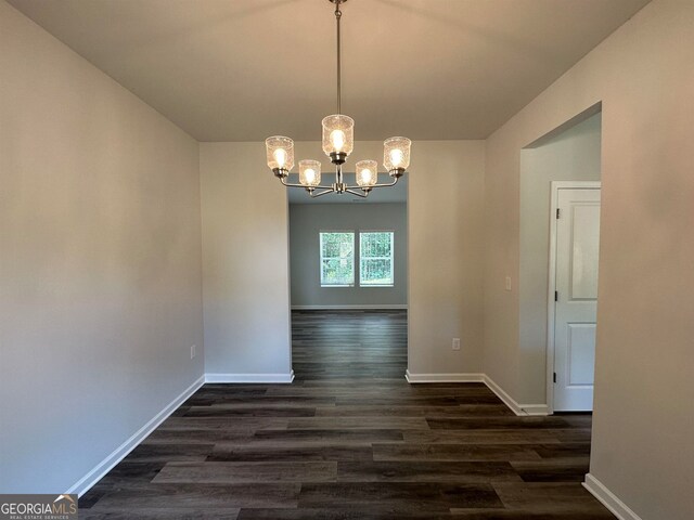 unfurnished dining area with dark hardwood / wood-style flooring and a chandelier