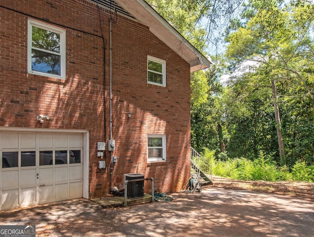 view of property exterior featuring central AC unit and a garage