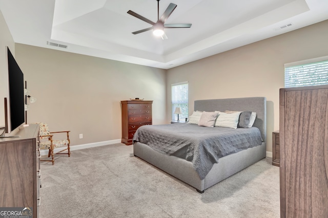 bedroom featuring ceiling fan, a raised ceiling, and light colored carpet