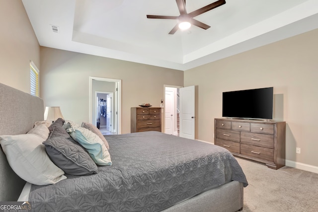 carpeted bedroom featuring ceiling fan, a raised ceiling, and ensuite bathroom