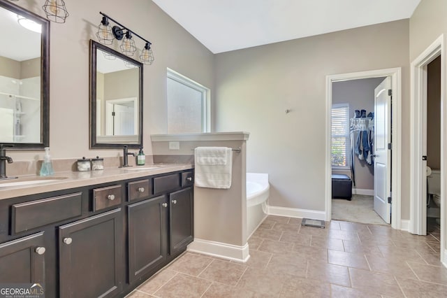 bathroom featuring toilet, tile patterned floors, a tub to relax in, and vanity