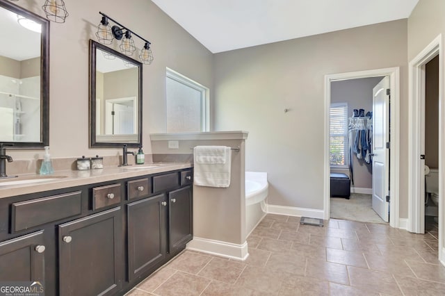 full bathroom featuring a garden tub, a sink, toilet, and double vanity