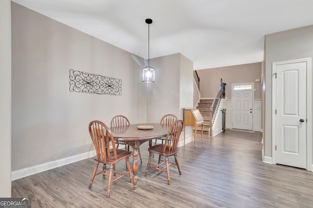 dining room featuring stairs, baseboards, vaulted ceiling, and wood finished floors