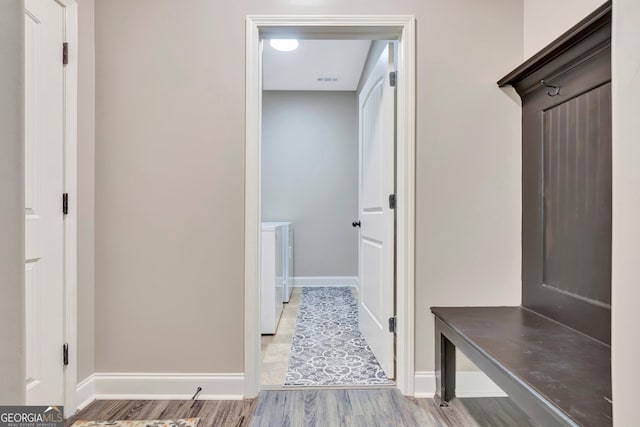 mudroom with washer and clothes dryer, baseboards, and wood finished floors