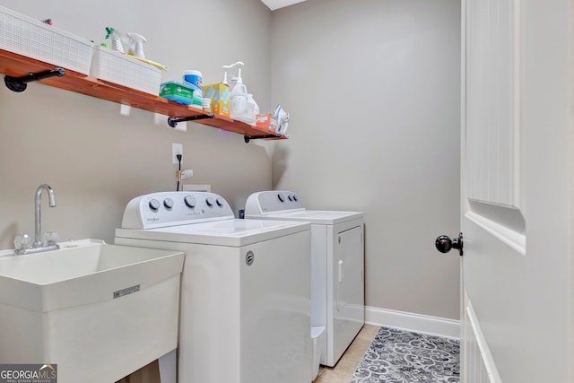 clothes washing area with laundry area, light tile patterned floors, baseboards, washing machine and clothes dryer, and a sink