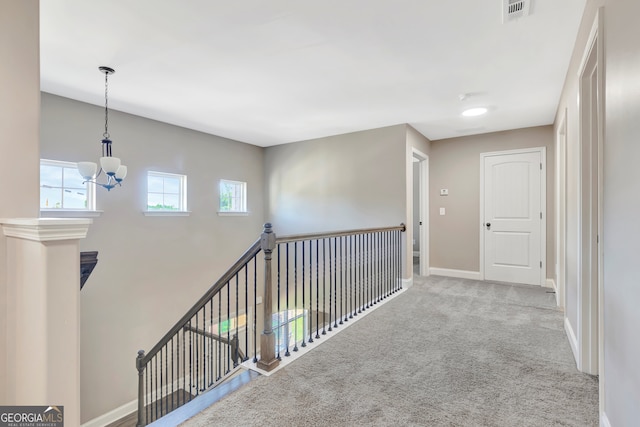 hall with carpet floors and an inviting chandelier