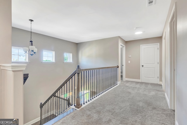 corridor with light carpet, baseboards, visible vents, and an upstairs landing