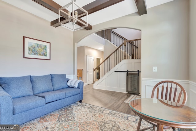 living room with beam ceiling, an inviting chandelier, and light wood-type flooring