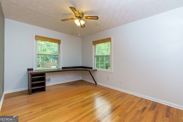 unfurnished office featuring a textured ceiling, light hardwood / wood-style floors, and plenty of natural light