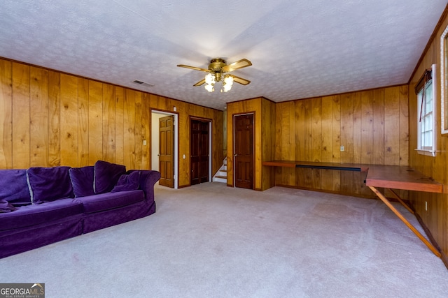 unfurnished living room featuring wood walls, carpet, and ceiling fan