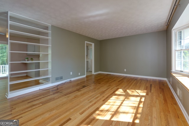 empty room with light hardwood / wood-style flooring and a textured ceiling