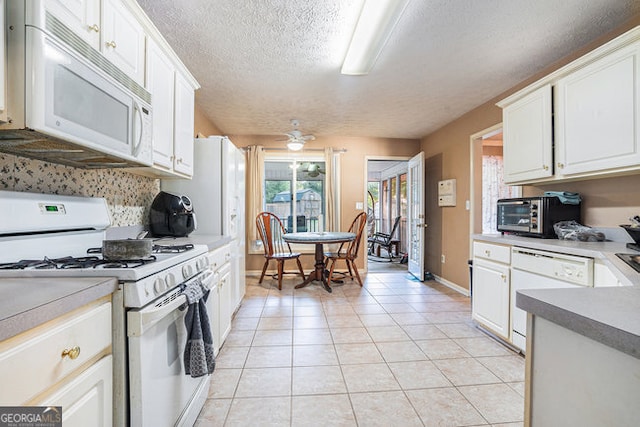 kitchen featuring a textured ceiling, white appliances, white cabinetry, and light tile patterned floors