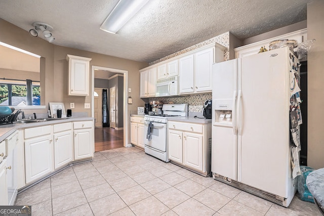 kitchen featuring sink, white appliances, a textured ceiling, light tile patterned floors, and white cabinets