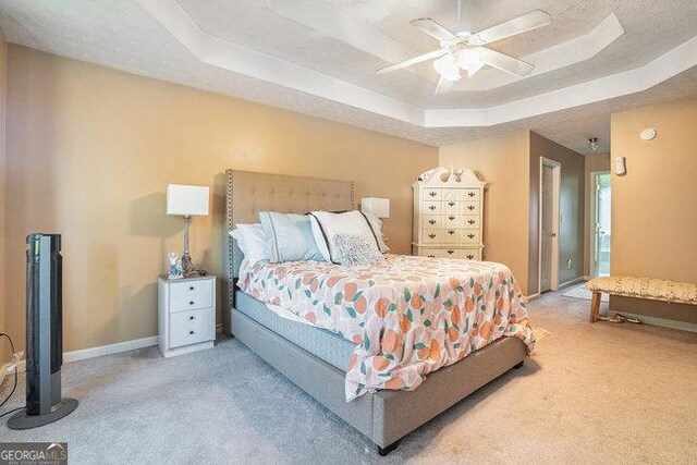 carpeted bedroom featuring ceiling fan and a tray ceiling