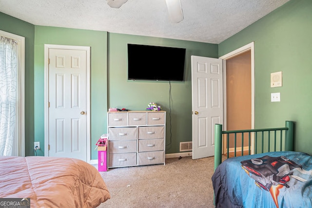 bedroom featuring ceiling fan, light carpet, and a textured ceiling