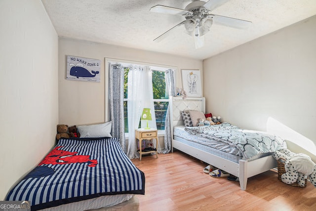 bedroom featuring ceiling fan, a textured ceiling, and wood-type flooring