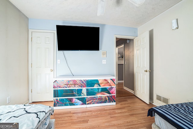 bedroom with a textured ceiling, ceiling fan, and hardwood / wood-style flooring