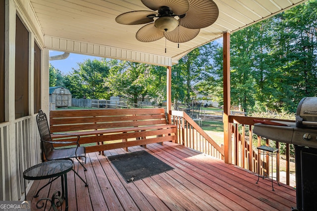 deck with ceiling fan, a grill, and an outbuilding