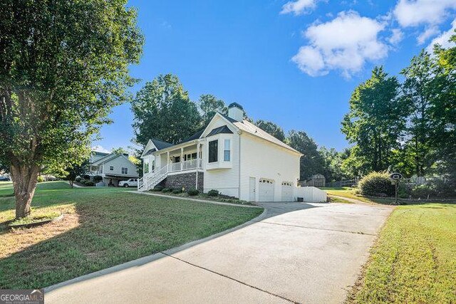 view of side of home featuring a porch, a garage, and a yard