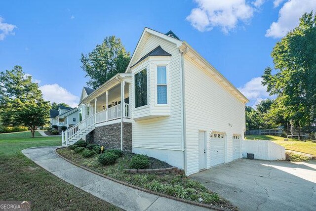 view of property exterior with a garage, a yard, and a porch