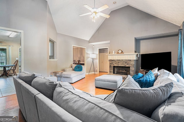 living room with ceiling fan, a fireplace, high vaulted ceiling, and light hardwood / wood-style floors