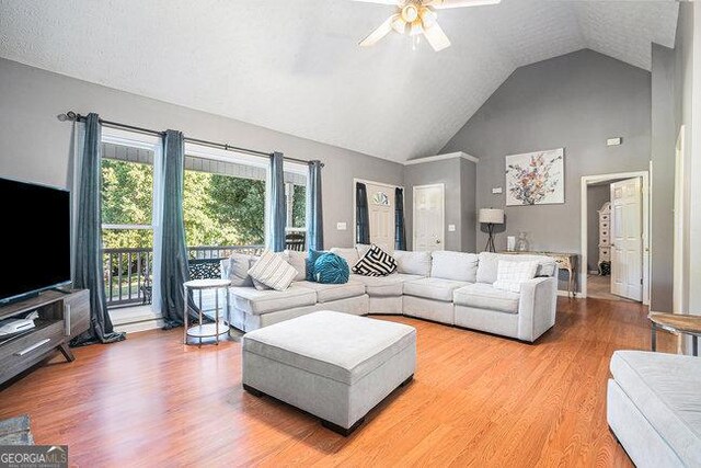 living room featuring ceiling fan, high vaulted ceiling, and wood-type flooring