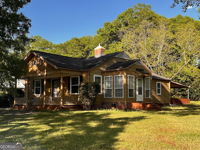 back of property with a porch, crawl space, a chimney, and a lawn